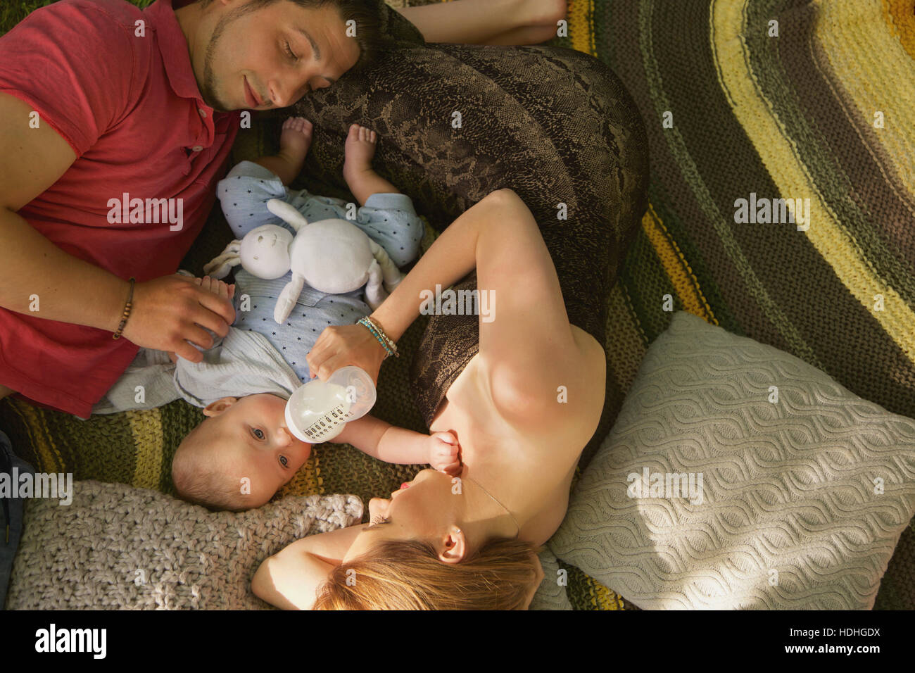 Direkt oben geschossen Fütterung Baby Boy mit Flasche und Frau Mann am Bett zu Hause entspannen Stockfoto