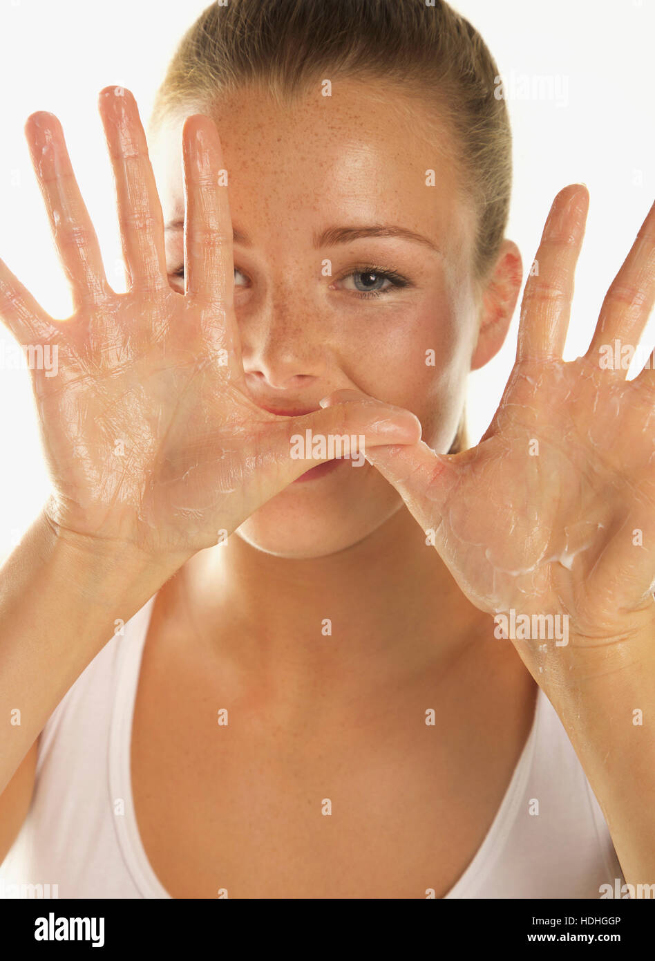 Close-up Portrait der schönen Frau, die Bodylotion auf Handflächen vor weißem Hintergrund Stockfoto