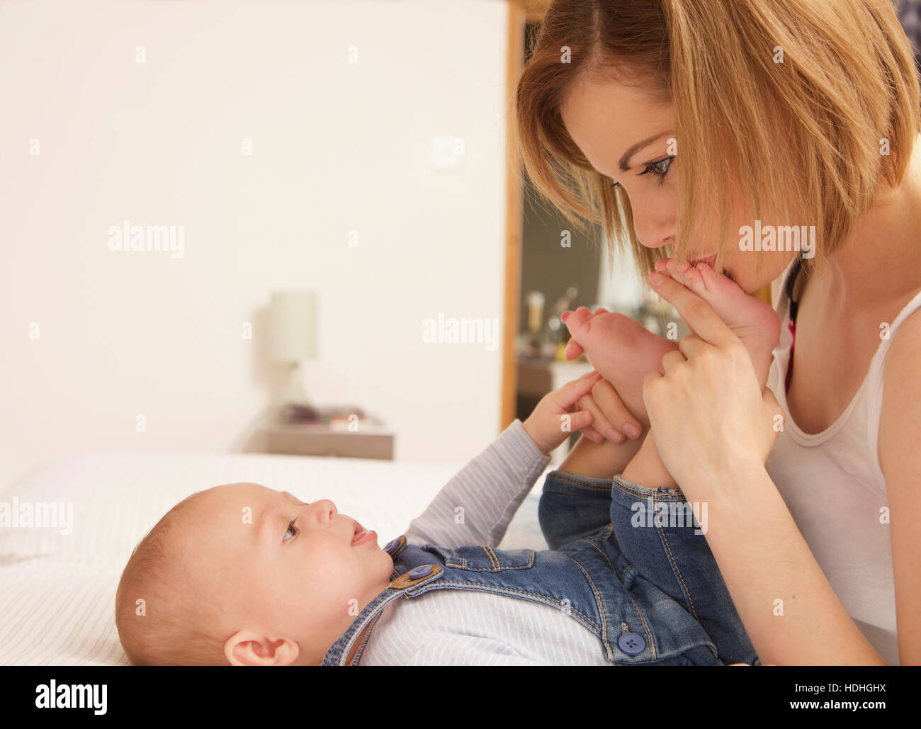 Liebevolle Mutter küssen Baby Boy Fuß zu Hause Stockfoto