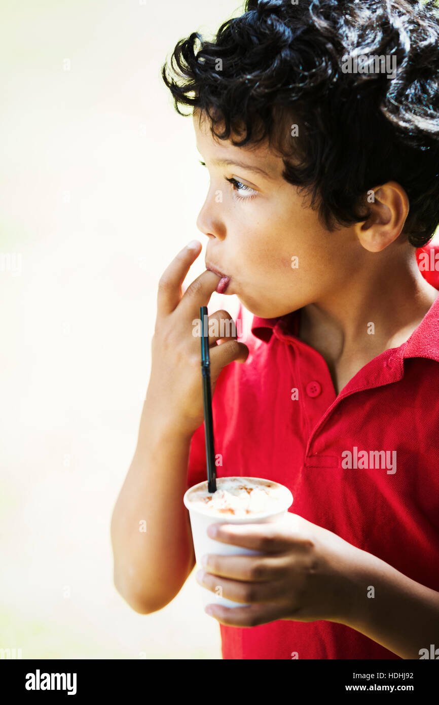 Junge hält einen Drink in einem Plastikbecher mit Stroh. Stockfoto