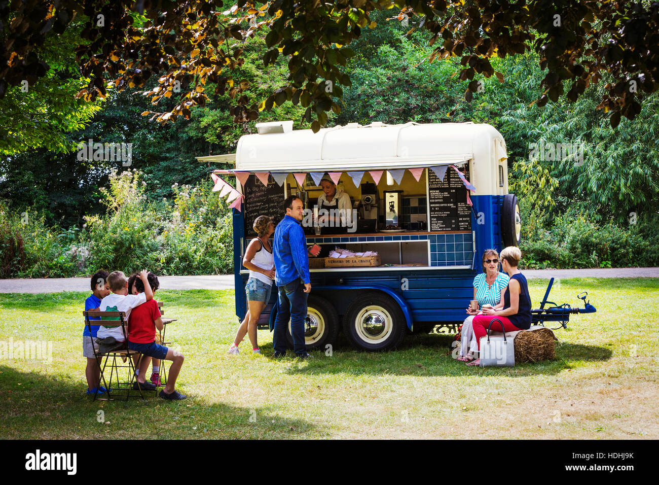 Menschen auf einen blauen mobilen Coffee Shop auf einer Wiese. Stockfoto