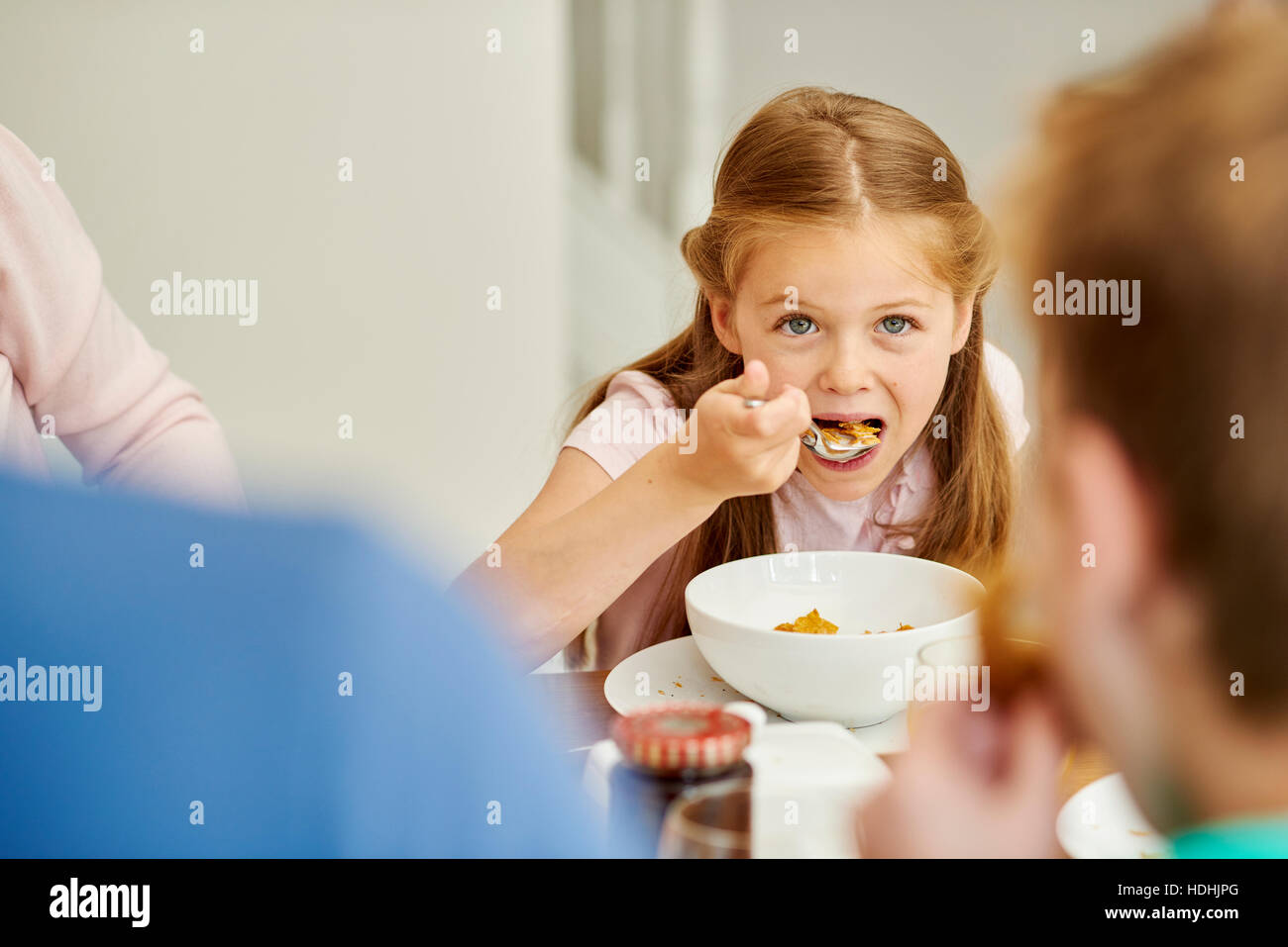 Eine Familie frühstücken. Ein Mädchen mit einem Löffel Müsli zu essen. Stockfoto