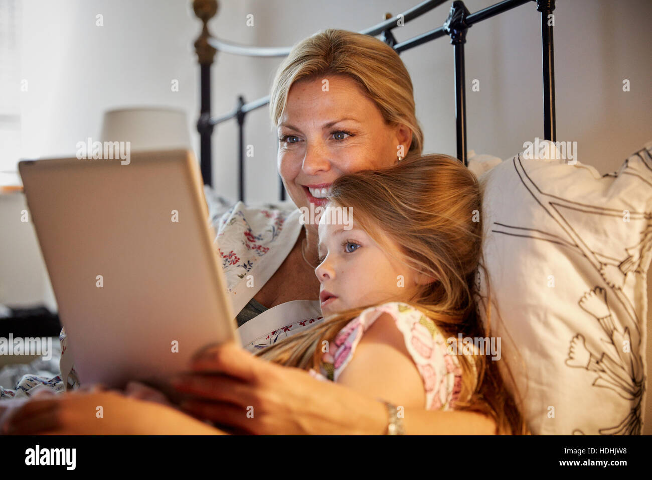 Eine Frau und ein Kind im Bett einen Laptop-Bildschirm sitzt. Stockfoto