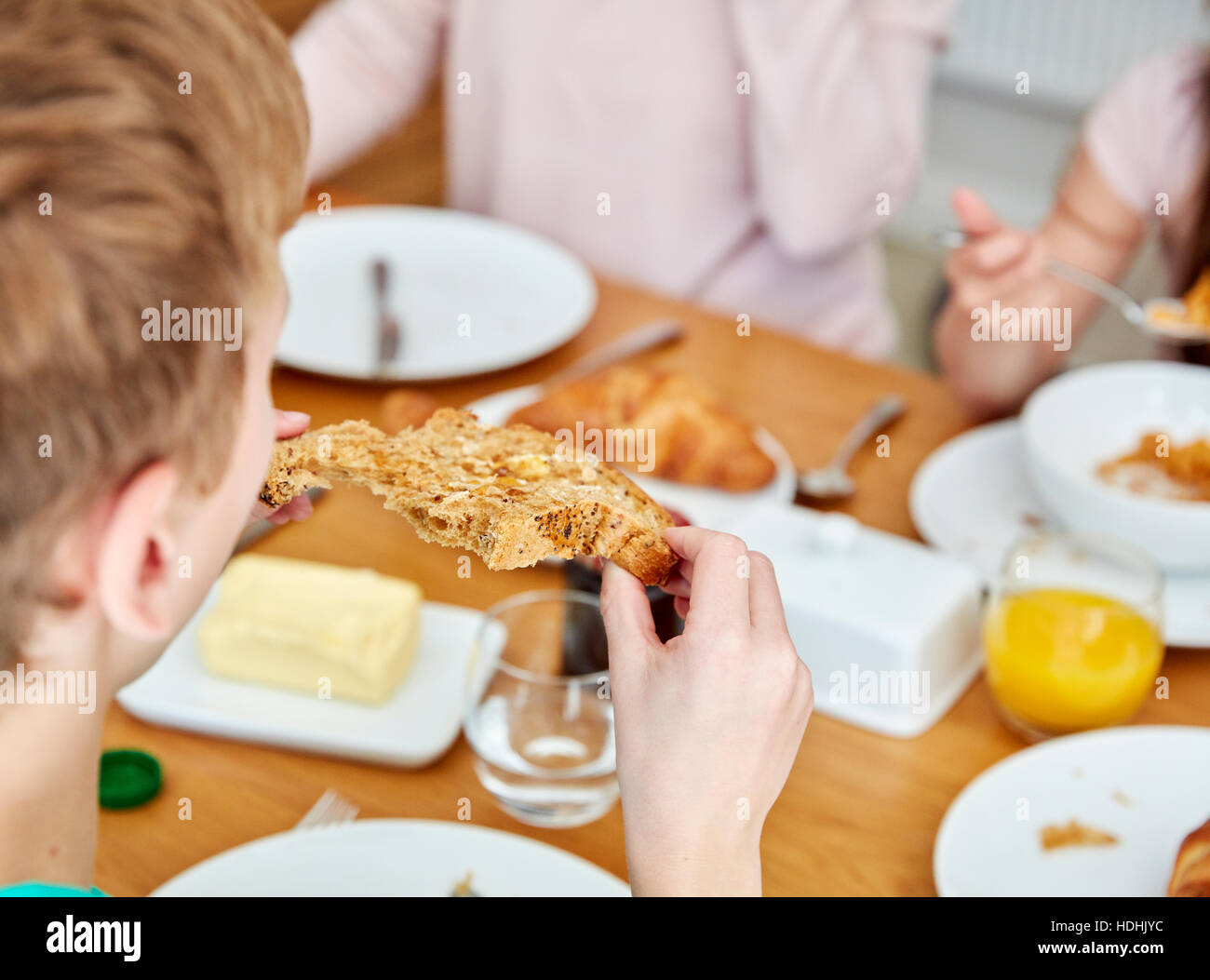 Eine Familie sitzt beim Frühstück, Essen Croissants. Stockfoto