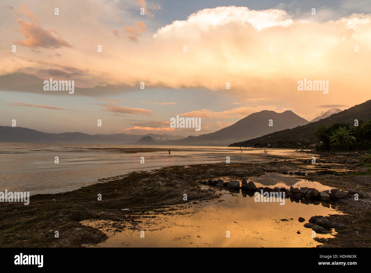 Bunte Wolken über Lake Atitlan, Guatemala bei Sonnenuntergang.  Neigung der inaktiven San Pedro Volcano auf rechten Seite, mit doppelter Spitze des Atitlan Vulkan dahinter ein Stockfoto Bunte Wolken über Lake Atitlan, Guatemala bei Sonnenuntergang.  Neigung der inaktiven San Pedro Volcano auf rechten Seite, mit doppelter Spitze des Atitlan Vulkan dahinter ein Stockfoto