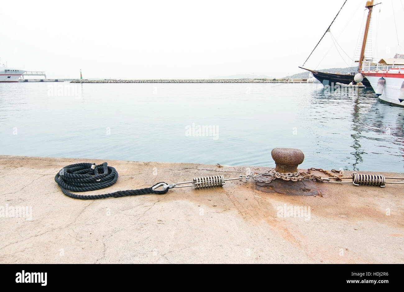 Liegeplatz mit rostigen Knopf, Kette und Seil an einem bewölkten Tag in Ibiza, Balearen, Spanien. Stockfoto