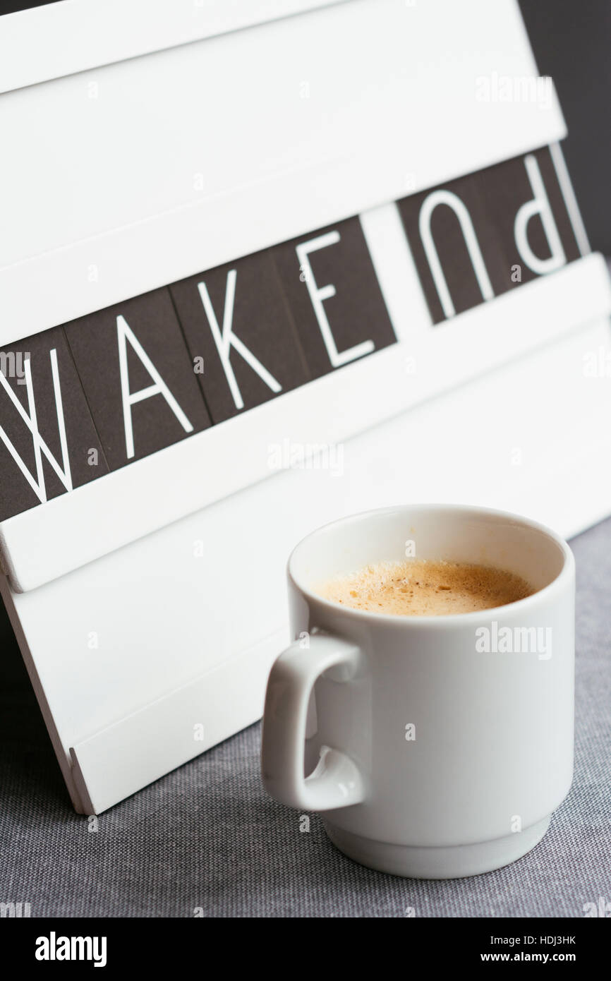 Tasse Kaffee vor ein Board, das sagt "wake up" Stockfoto