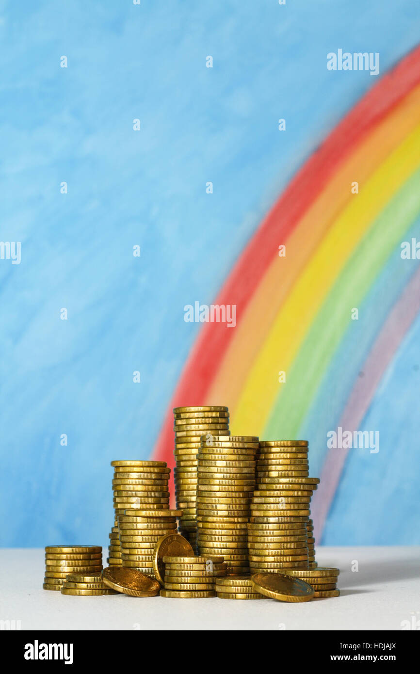 Goldmünzen mit einem blauen Himmel und Regenbogen aus Glück, Einsparungen, Vermögen und den Topf voll Gold am Ende des Regenbogens. Stockfoto