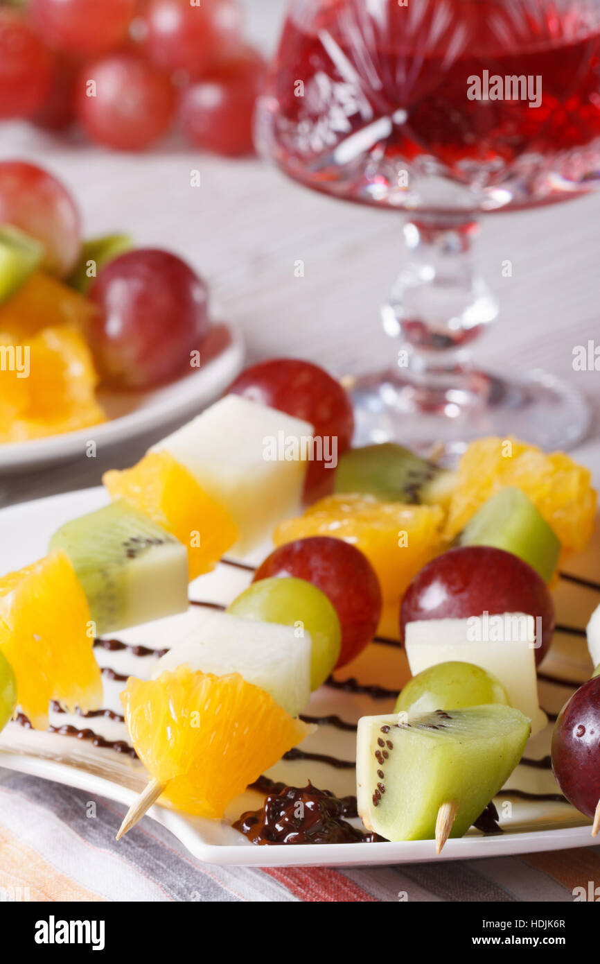 Frisches Obst auf Spieße und roten Wein close-up auf dem Tisch. vertikale Stockfoto