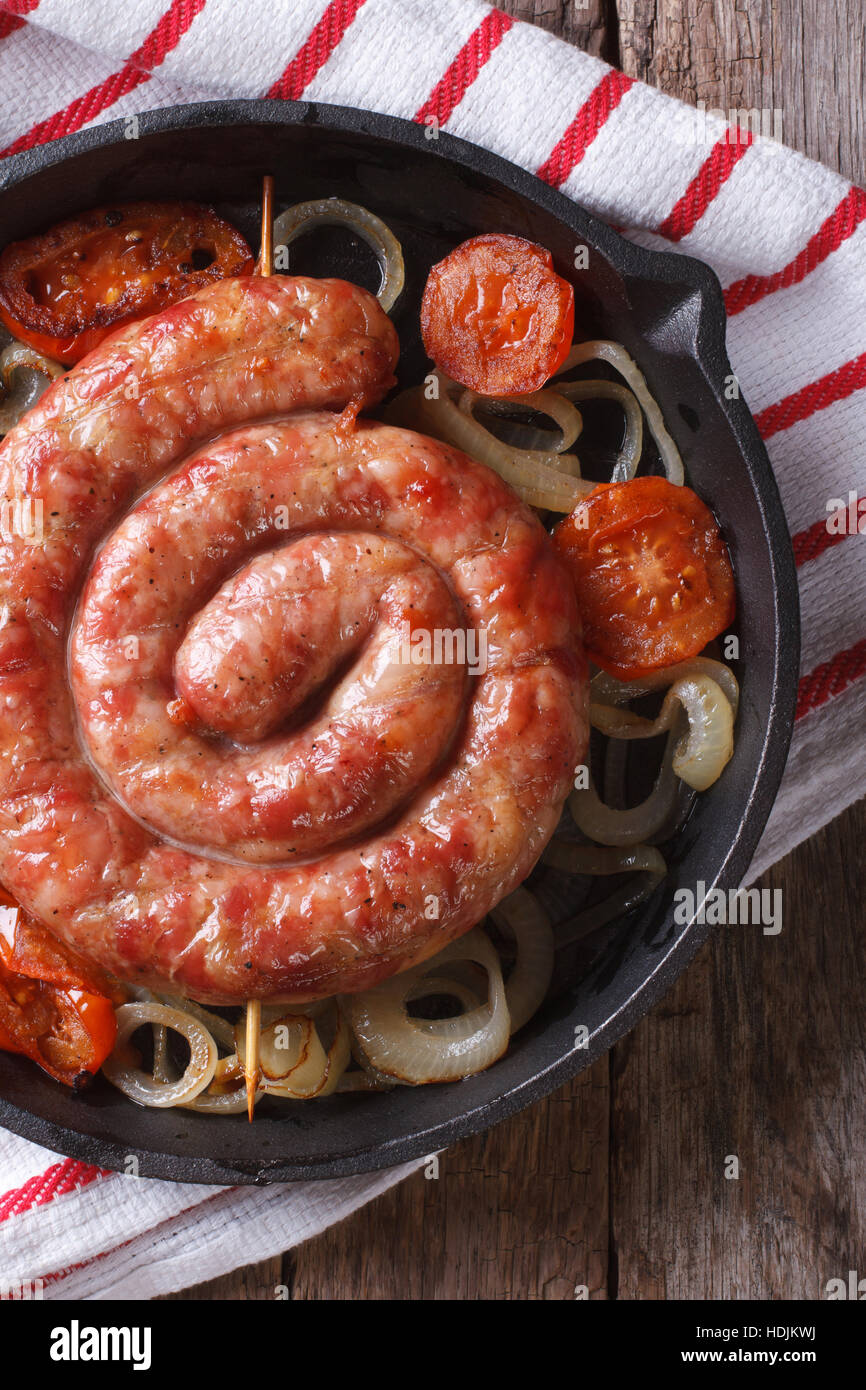 Gebratene Wurst mit Zwiebeln und Tomaten in eine Pfanne Makro. vertikale Ansicht von oben Stockfoto