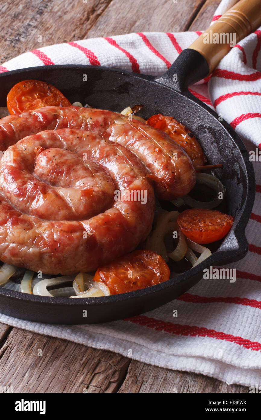 Bratwürste mit Zwiebeln und Tomaten in eine Pfanne Nahaufnahme. vertikale Stockfoto