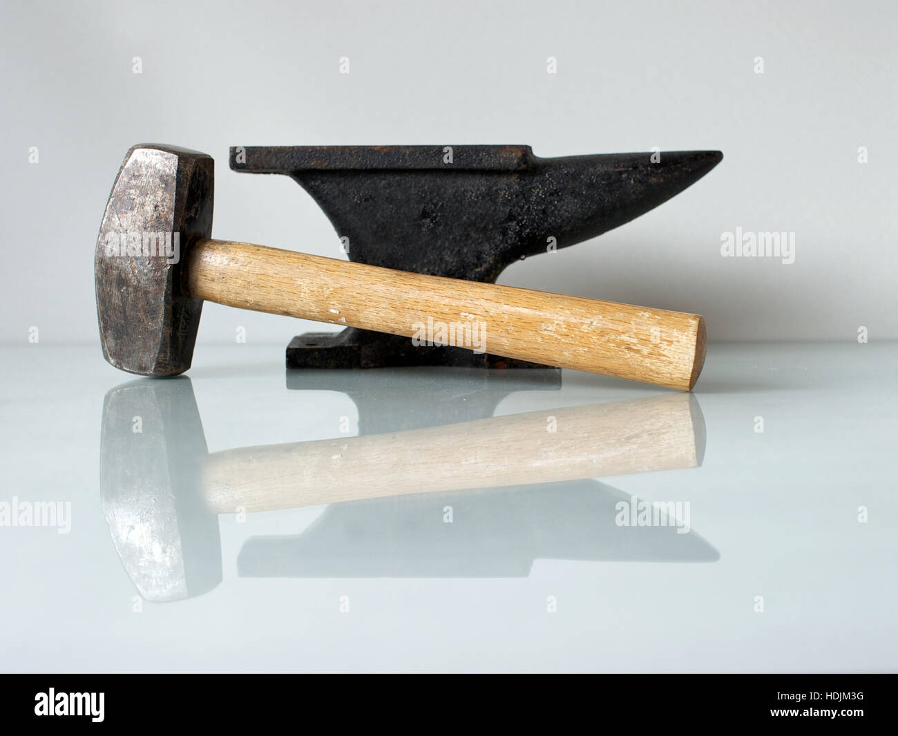 Stillleben mit Schmied Werkzeuge, einem Hammer und einem alten Amboss auf einer Glasplatte mit weißem Hintergrund. Stockfoto