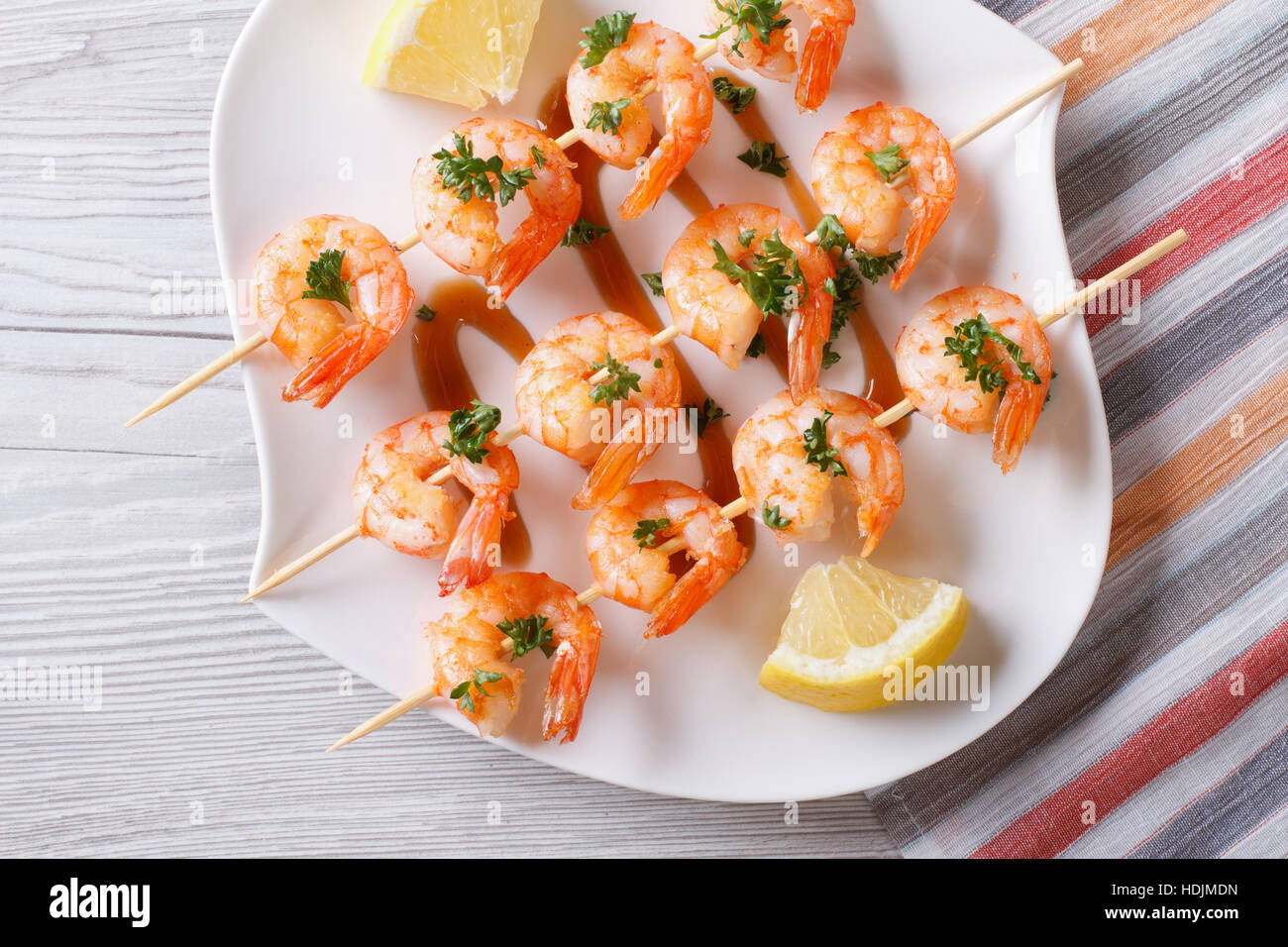 Gegrillte Garnelen am Spieß mit Zitrone auf eine Platte Nahaufnahme. horizontale Ansicht von oben Stockfoto