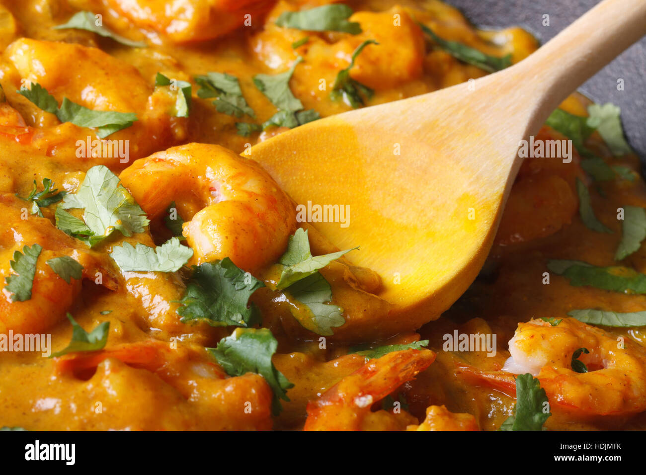 Garnelen in Curry-Sauce mit einem Holzlöffel Makro. horizontale Stockfoto