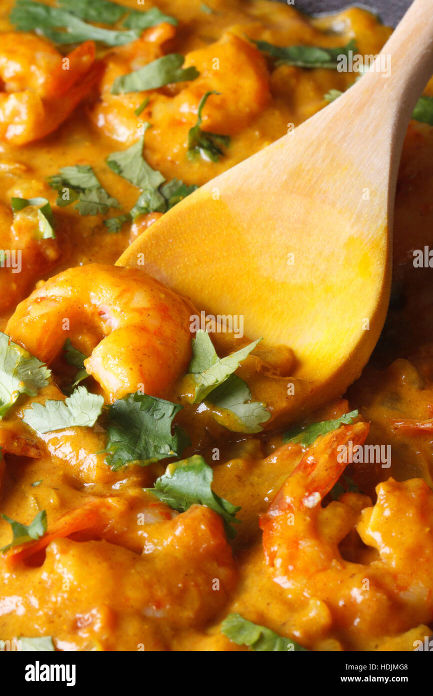 Garnelen in Curry-Sauce mit einem Holzlöffel Makro. Vertikal Stockfoto