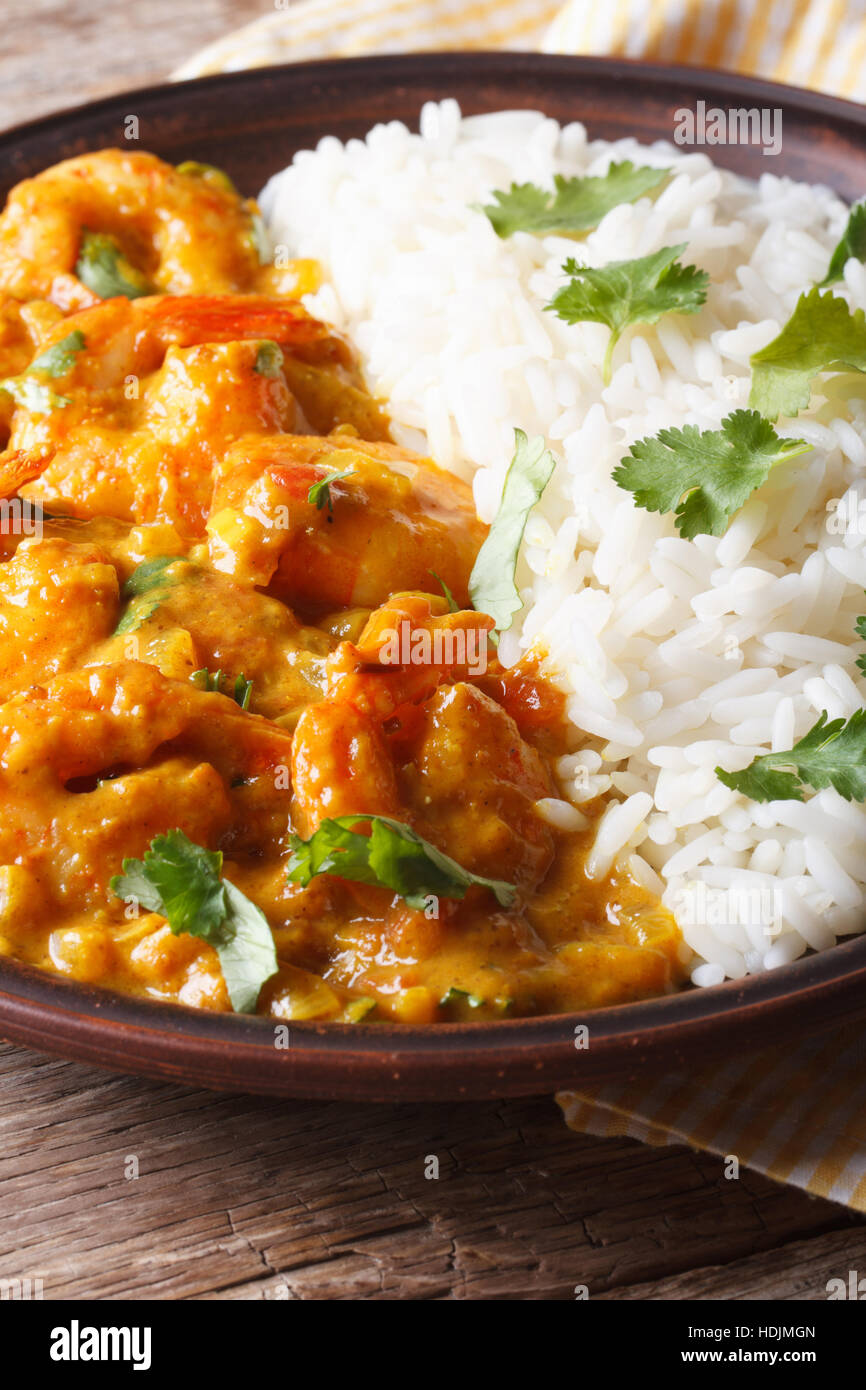 Garnelen in Curry-Sauce mit Reis und Koriander Closeup auf einem Teller ...