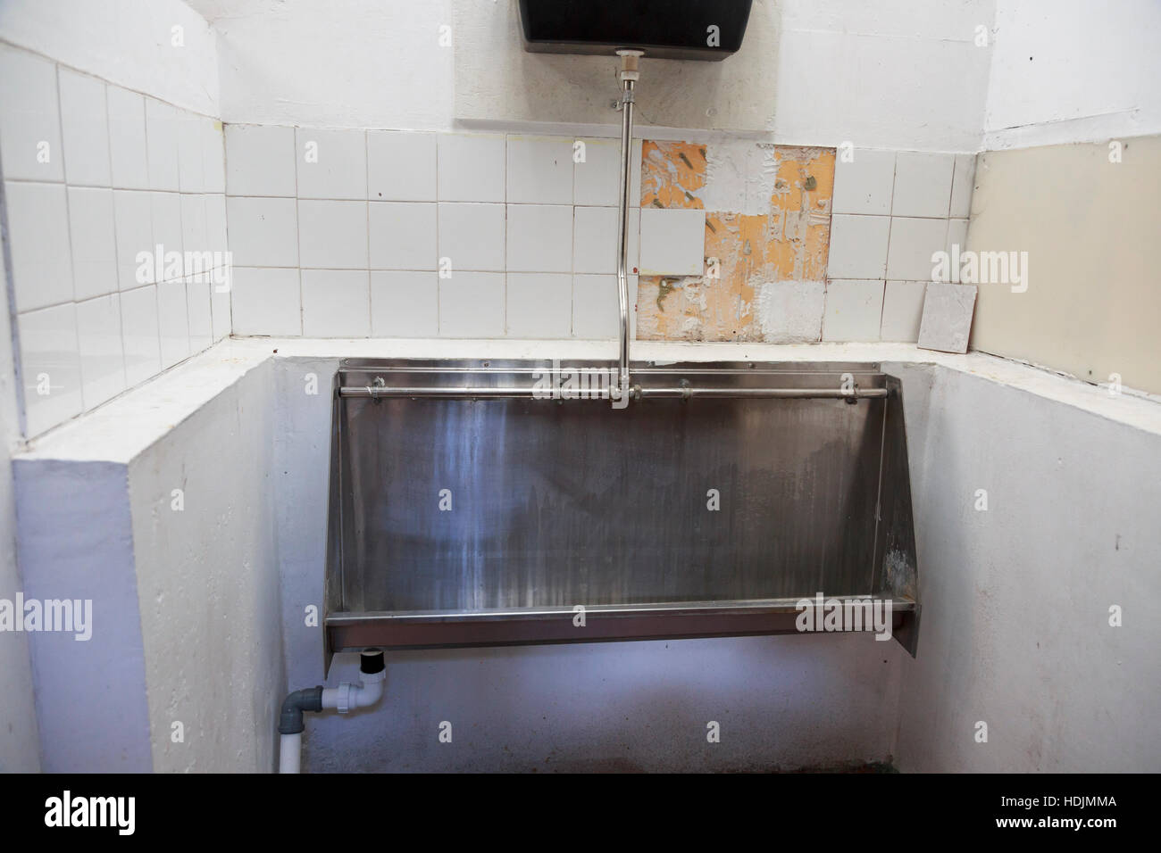 Herren WC Urinal schmutzig mit gebrochenen Fliesen Stockfoto