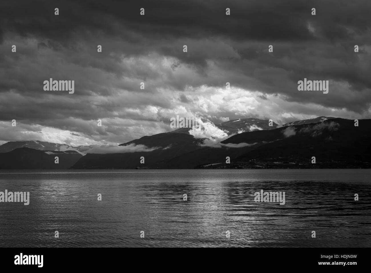 Ein Fjord in dramatische Blitze. Dunkle Wolken bilden auf der anderen Seite des Fjords, mit leichten Wolken aus dem Berg Stockfoto
