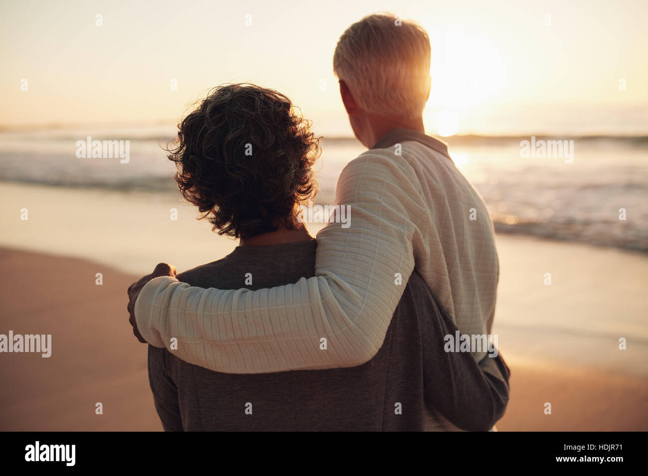 Rückansicht des Ehepaar im Ruhestand erstaunlichen Sonnenuntergang erschossen. Ältere Mann und Frau stehen zusammen am Strand. Stockfoto