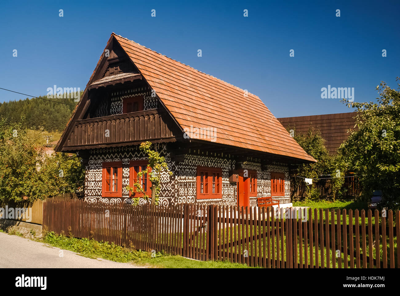 Altes Holzhaus mit weißen Gemälde an der Wand, umgeben von viel Grün in Cicmany, altes Dorf in der Slowakei. Stockfoto
