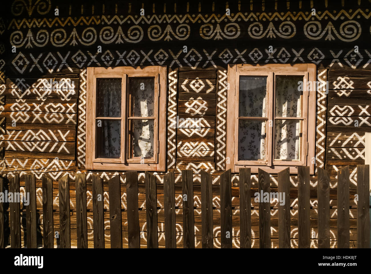 Altes Holzhaus mit zwei Fenstern und vielen weißen Ornamenten bemalt an seiner Wand in Cicmany, altes Dorf in der Slowakei. Stockfoto