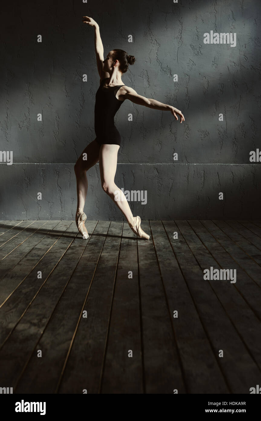 Junge Tänzerin, die in den dunklen beleuchteten Raum durchführen Stockfoto
