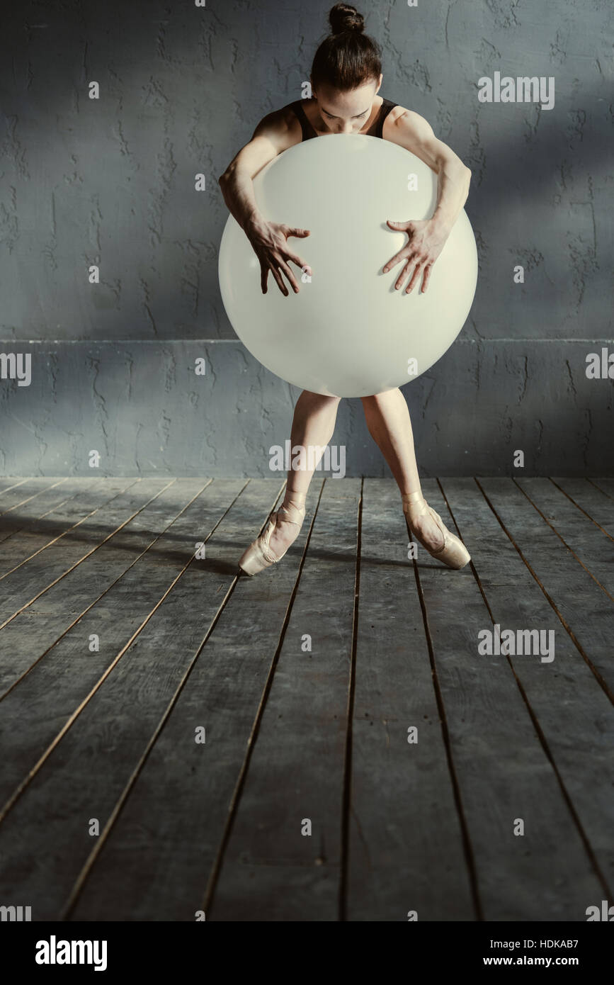 Emotionslos Ballett-Tänzerin umarmt den weißen Ballon im studio Stockfoto