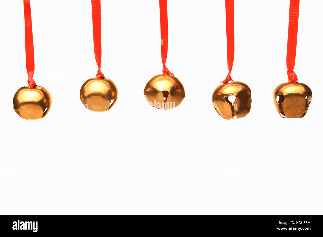 Fünf jingle Glocken hängen aus roten Bändern vor weißem Hintergrund Stockfoto