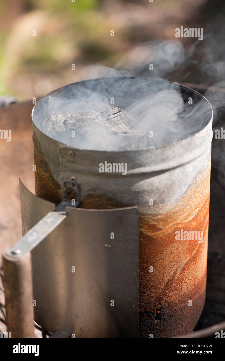 Schornstein-Starter und Rauch. Vorbereitung der Grill mit Holzkohle in Brand. Stockfoto