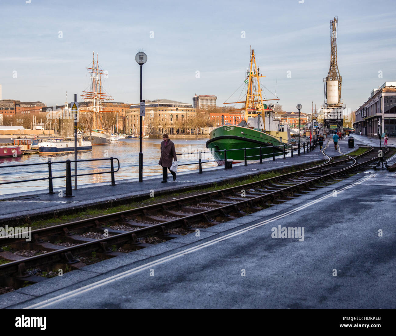 Ein Mann geht durch Bristol schwimmenden Hafen an einem Wintermorgen neben der Eisenbahn Krane und M vergossen museum Stockfoto