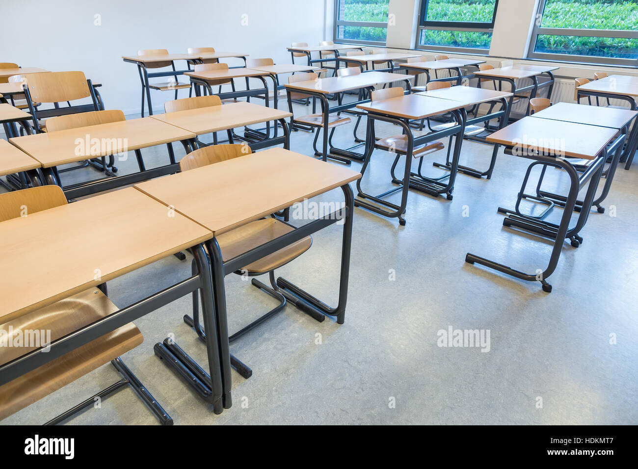 Reihen von Tischen und Stühlen im Klassenzimmer am Gymnasium Stockfoto
