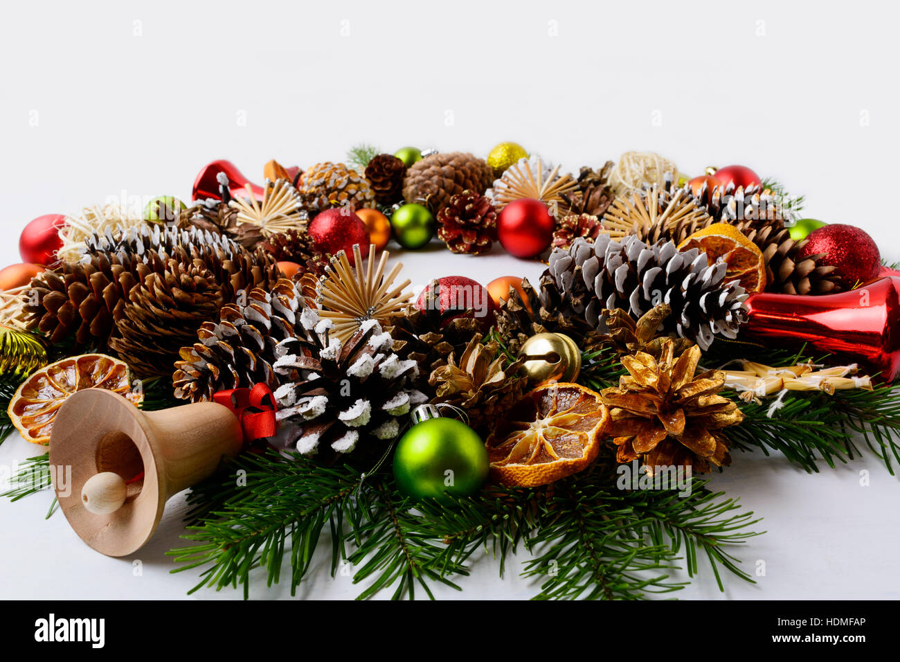 Weihnachts-Dekoration mit Glas und Holz Glöckchen. Weihnachtsgruß Hintergrund mit roten Ornamenten verziert Kranz. Stockfoto