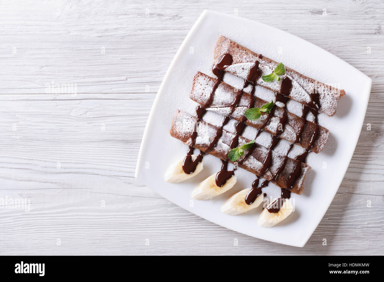 Schokolade Crepes mit Soße und Bananen auf einen Teller. horizontale Ansicht von oben Stockfoto