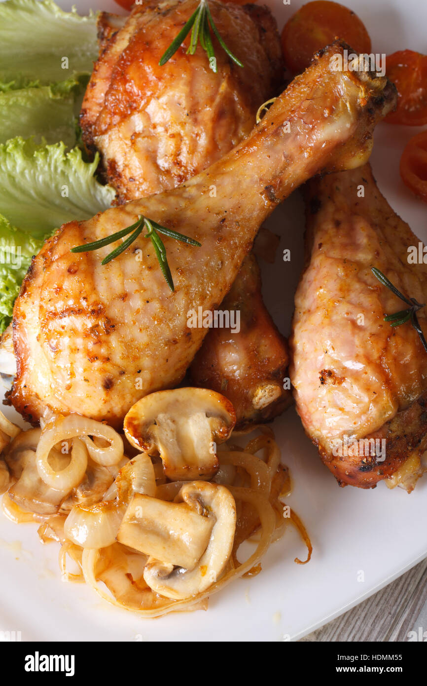 Fried Chicken Drumsticks mit Champignons und Rosmarin auf der Platte Nahaufnahme. vertikale Ansicht von oben Stockfoto