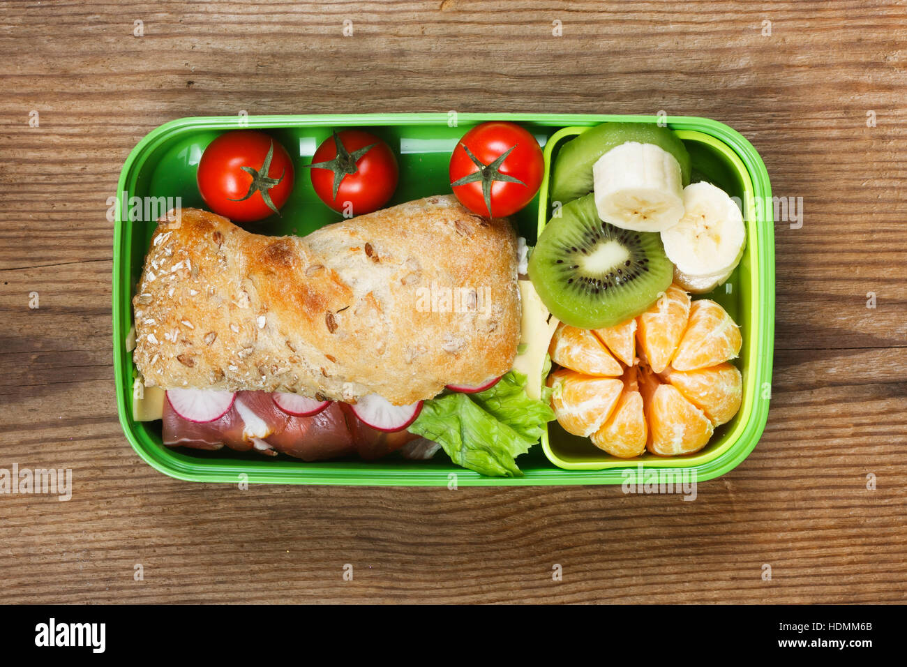 Lunchbox auf Holztisch. Schinken-Sandwich und Obst in Kunststoff-box Stockfoto