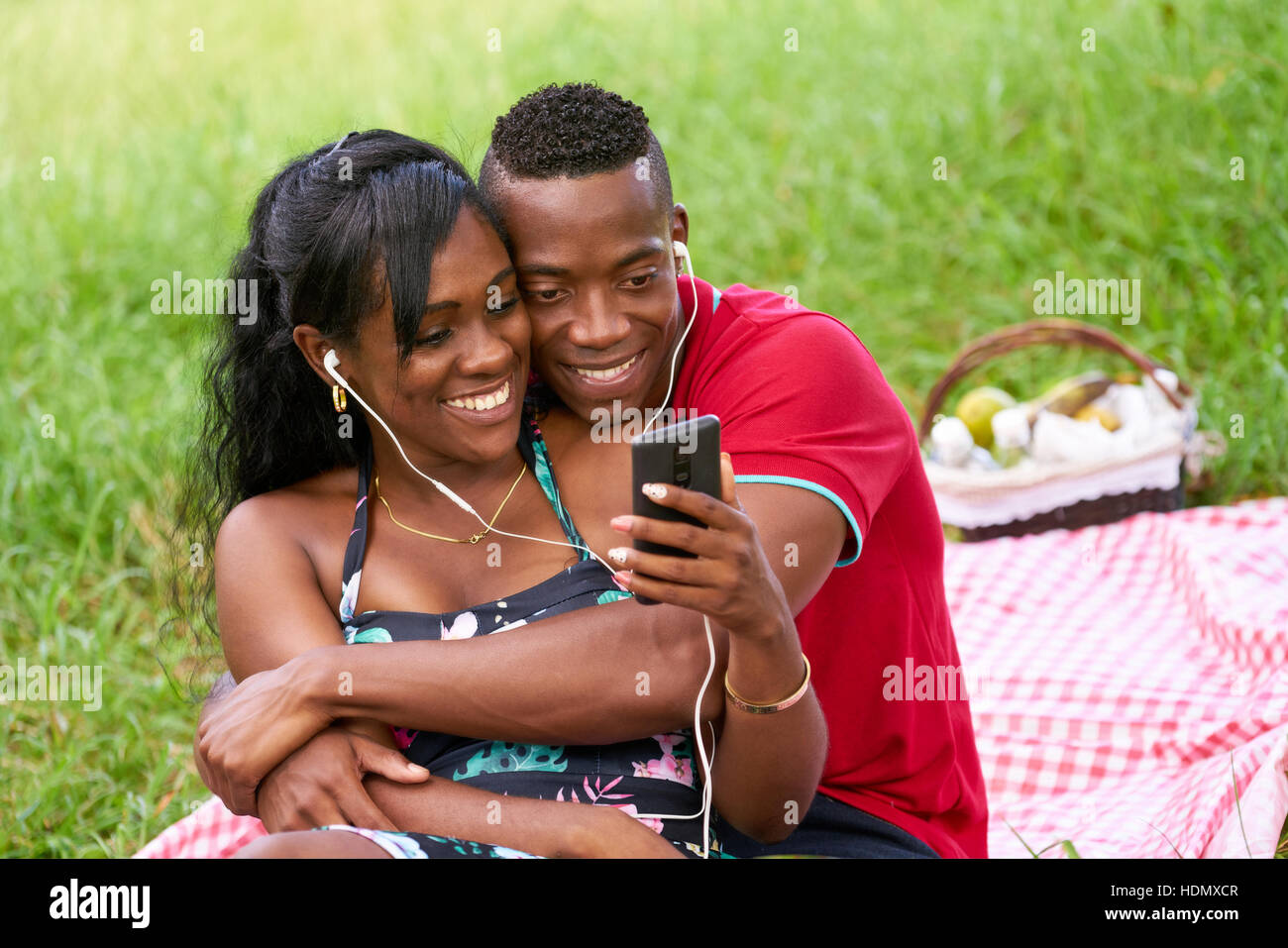Schwarzen Brautpaar Spaß im Stadtpark. Junge afrikanische amerikanische Mann und Frau anhören von Musik und Videos auf dem Handy. Stockfoto