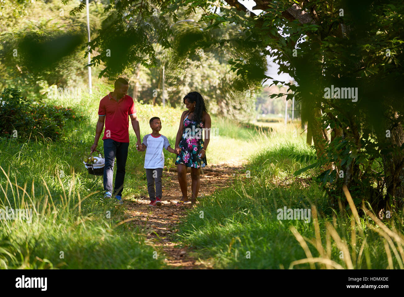 Brautpaar schwarz mit Sohn im Stadtpark spazieren. Afroamerikanische Familie mit junger Mann, Frau und Kind tun Picknick, Spaß im Freien. Stockfoto
