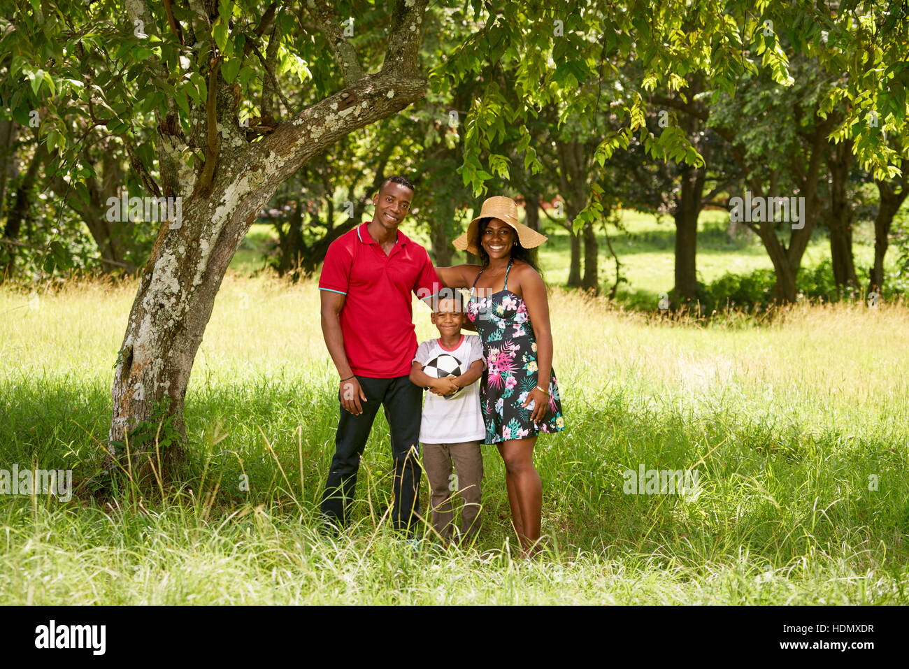 Glückliche schwarze Menschen im Park. Afroamerikanische Familie mit jungen Mama, Papa und Sohn Spaß mit Fußball. Portrait von Mann, Frau und junge mit Fussball b Stockfoto