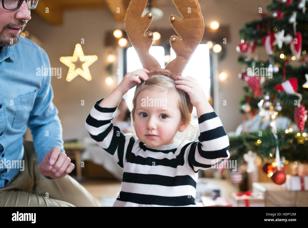Vater mit stahlharte am Weihnachtsbaum, Rentier-Geweih tragen Stockfoto