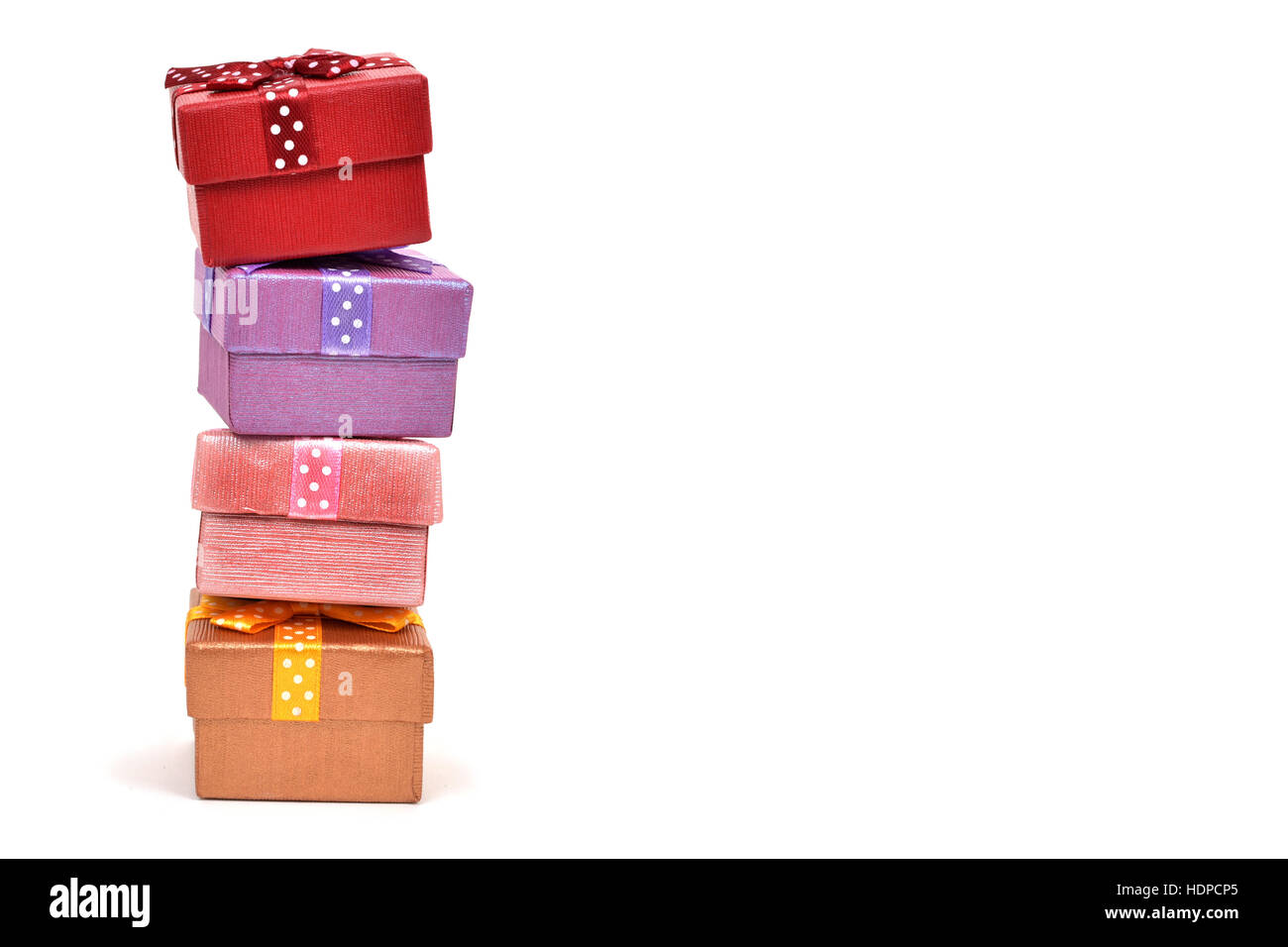 ein Stapel von Geschenken in verschiedenen Farben mit unterschiedlichen Bändern auf einem weißen Hintergrund, mit einem negativen Raum gebunden Stockfoto
