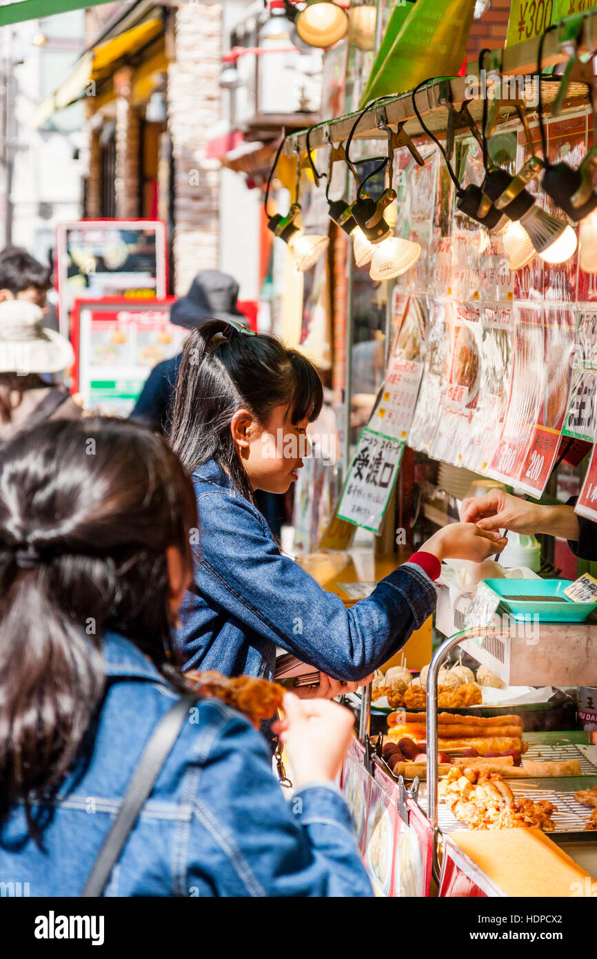 Japan, Kobe, Nankinmachi, Chinatown. Teenage japanische Frauen in blauen Jeans Jacke ihre Änderung übergeben werden nach dem Kauf von Lebensmitteln aus dem chinesischen Gerichte zum Mitnehmen. Stockfoto