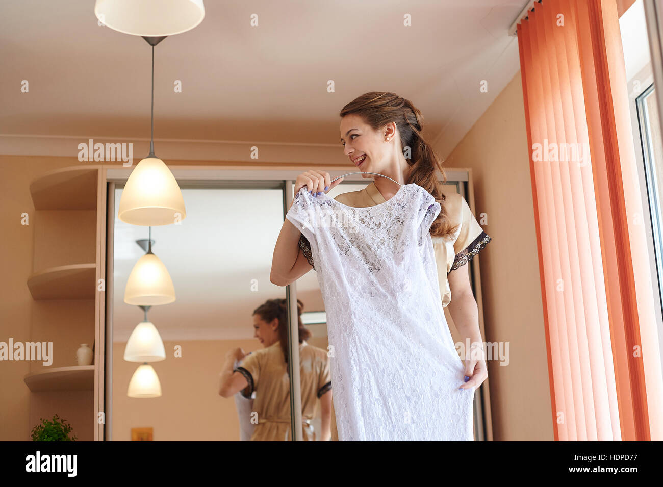 Braut ein Kleid vor Spiegel am Morgen der Hochzeit anprobieren Stockfoto