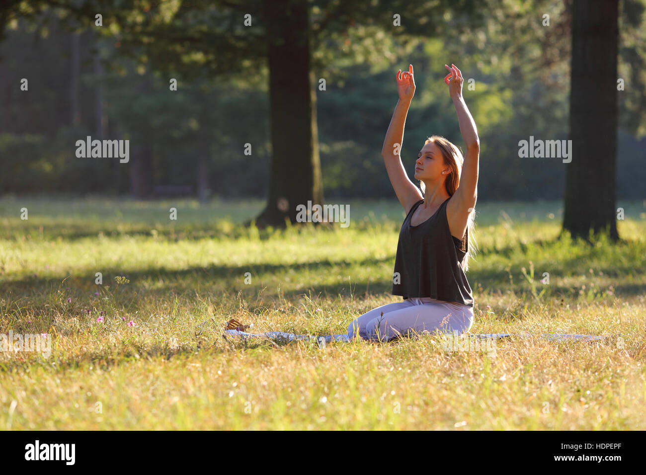 Junge Frau praktiziert Yoga im park Stockfoto