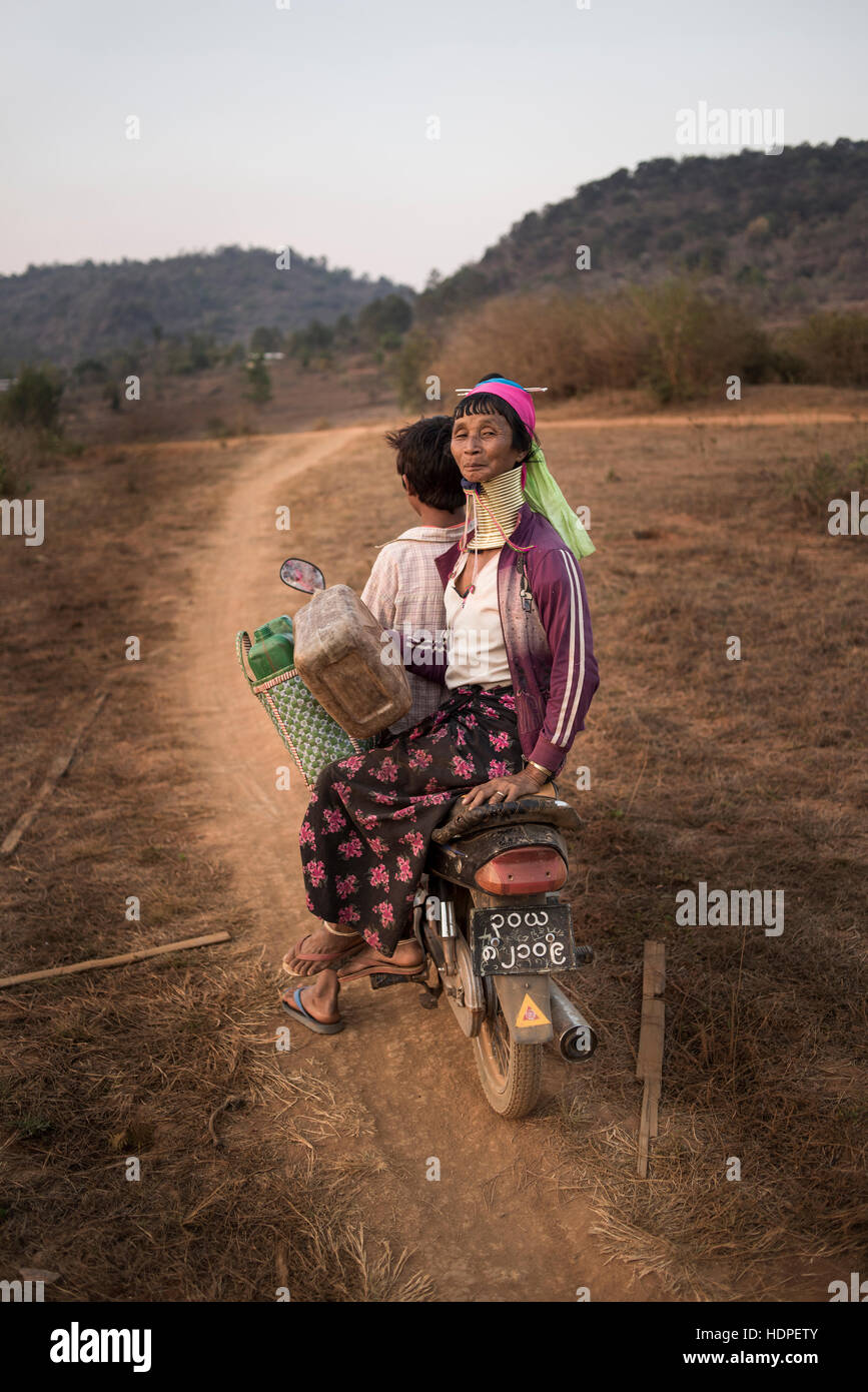 Kayan Frau Reiten auf einem Motorrad in einen Feldweg, Kayah State in Myanmar. Stockfoto