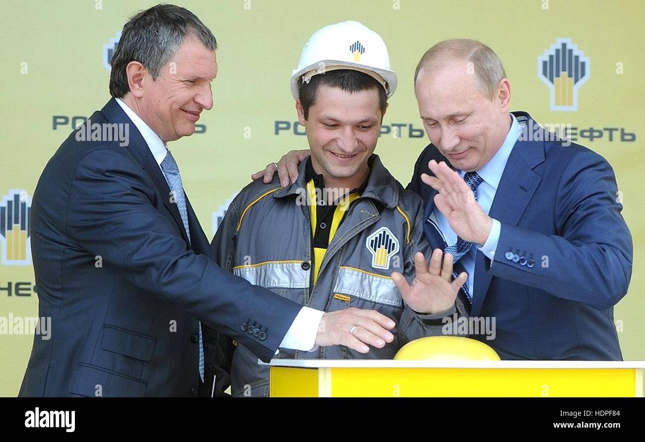 Der russische Präsident Vladimir Putin, Recht, lächelt, als er die Taste drückt, um das neue Tiefwasser Terminal an der Rosneft Tuapse Ölraffinerie mit Rosneft Vorsitzender Igor Sechin, links und ein Arbeiter 15. Juni 2012 in Tuapse, Russland zu starten. Stockfoto