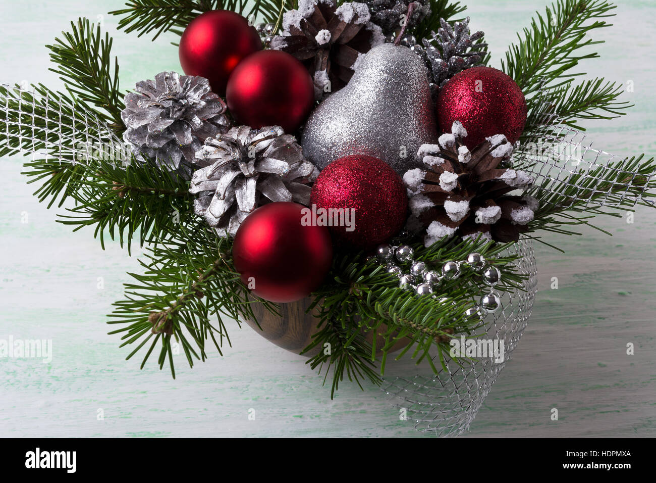 Weihnachtsarrangement mit roten Kugeln und dekorierte Pinienzapfen. Weihnachts-Dekoration mit Tannenzweigen und roten Ornamenten. Weihnachten Silber glitter ta Stockfoto