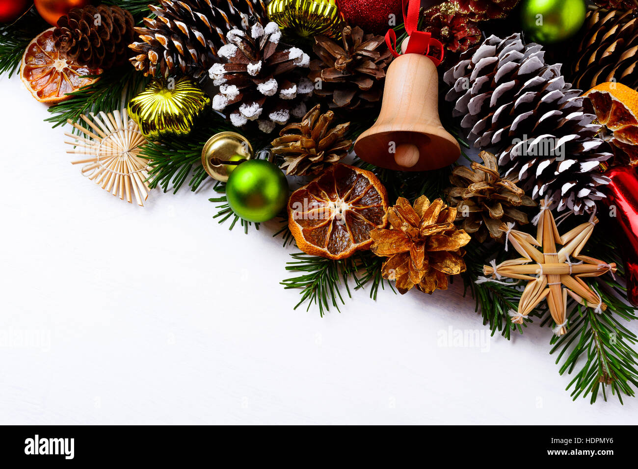 Weihnachtsgruß Hintergrund mit handgemachten hölzernen Jingle Bell und Kiefer Kegel. Weihnachts-Dekoration mit grünen Ornamenten und Orangenscheiben getrocknet. Kopie Stockfoto