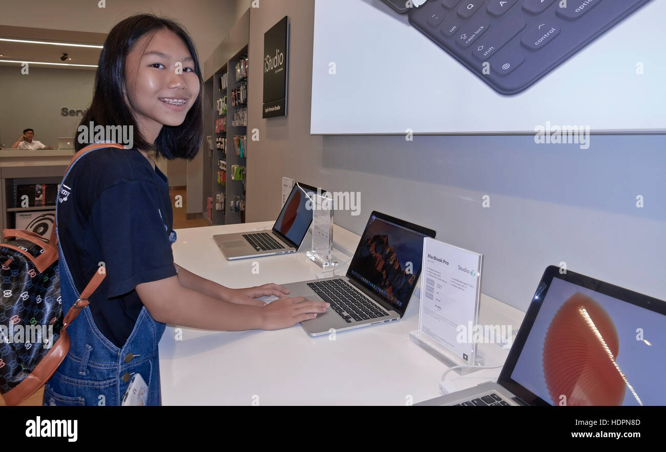 Asiatische Teen Mädchen mit einem 2016 Apple MacBook pro Notebook-Laptop-Computer zum Verkauf im lokalen Apple-Shop. Thailand S. E. Asien Stockfoto