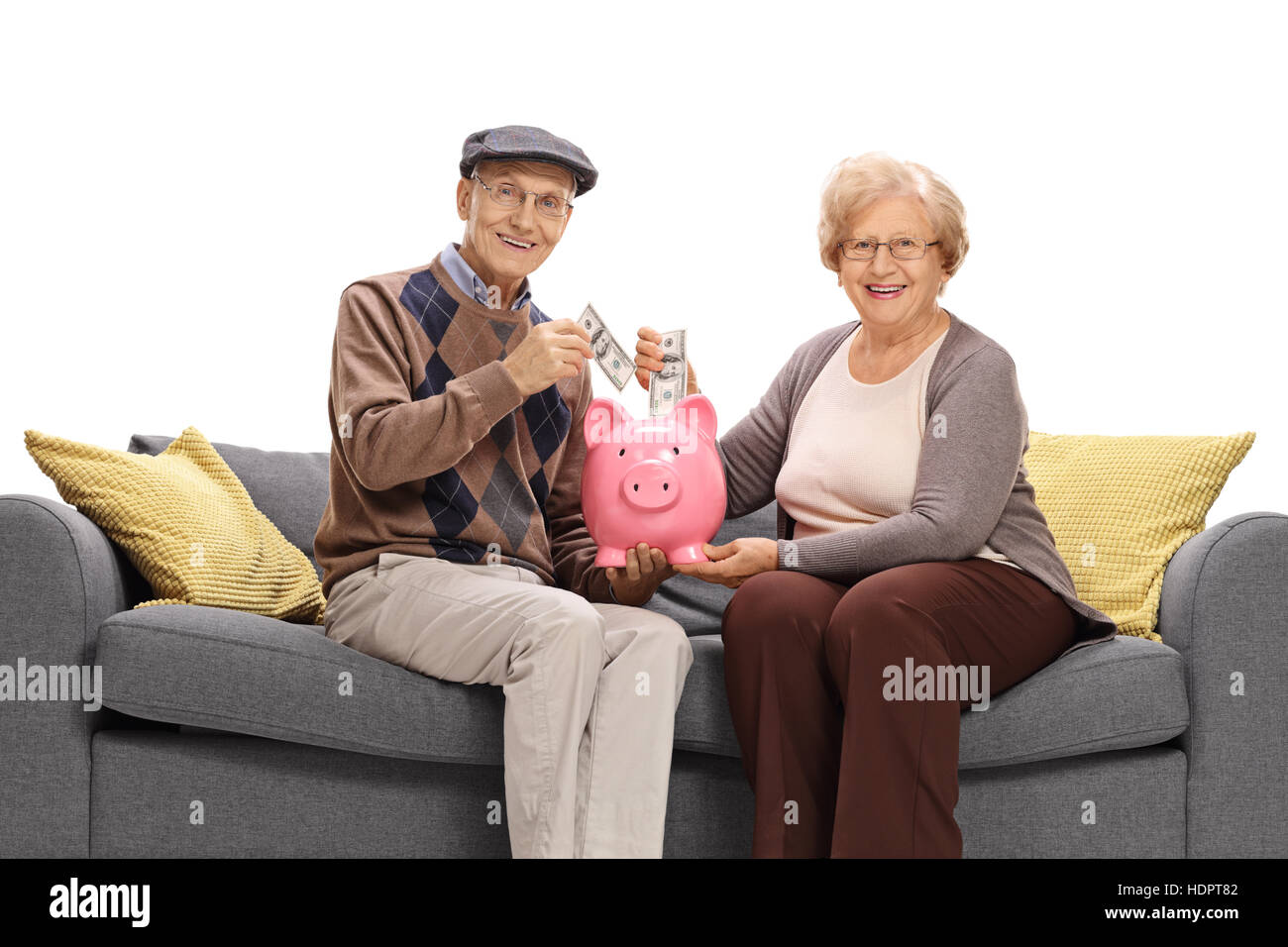 Glücklich Senioren, Geld in ein Sparschwein und schaut in die Kamera, die isoliert auf weißem Hintergrund Stockfoto