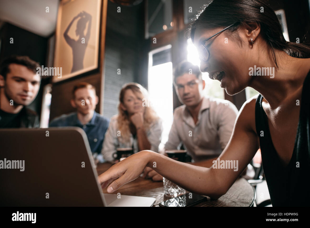 Junge Frau auf Laptop zeigen und diskutieren mit Freunden. Gruppe von Jugendlichen im Café Blick auf Laptop-Computer. Stockfoto